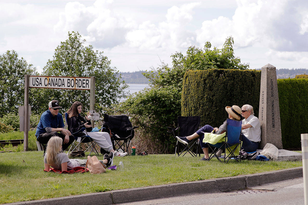 In this photo taken May 17, 2020, de Rham family members from the U.S. and Canada visit at the border between the countries in Peace Arch Park, in Blaine, Wash. With the border closed to nonessential travel amid the global pandemic, families and couples across the continent have found themselves cut off from loved ones on the other side. But the recent reopening of Peace Arch Park, which spans from Blaine into Surrey, British Columbia, at the far western end of the 3,987-mile contiguous border, has given at least a few separated parents, siblings, lovers and friends a rare chance for some better-than-Skype visits. (Elaine Thompson/Associated Press)