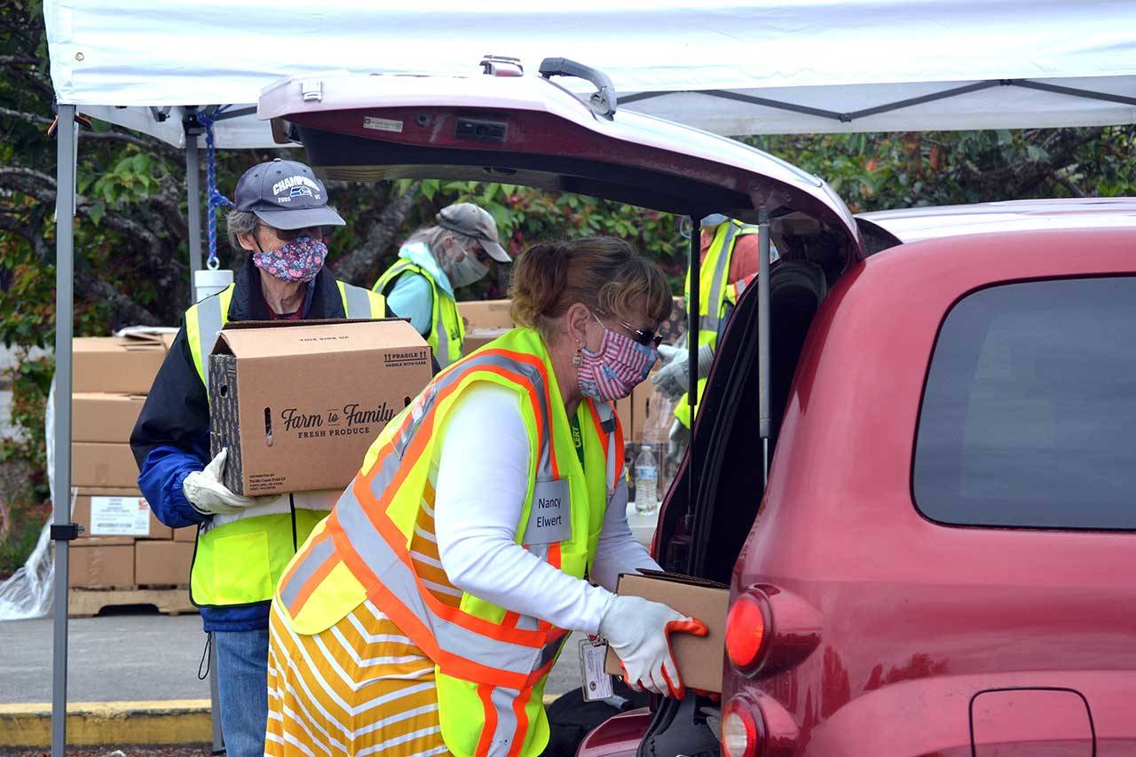Volunteers Bruce Leigh and Nancy Elwert with Community Emergency Response Teams (CERT) place food boxes in a trunk June 10 at Sequim High School. Free food boxes are available through the USDA from 11 a.m. to 2 p.m. Wednesdays through Aug. 19. (Matthew Nash/Olympic Peninsula News Group)