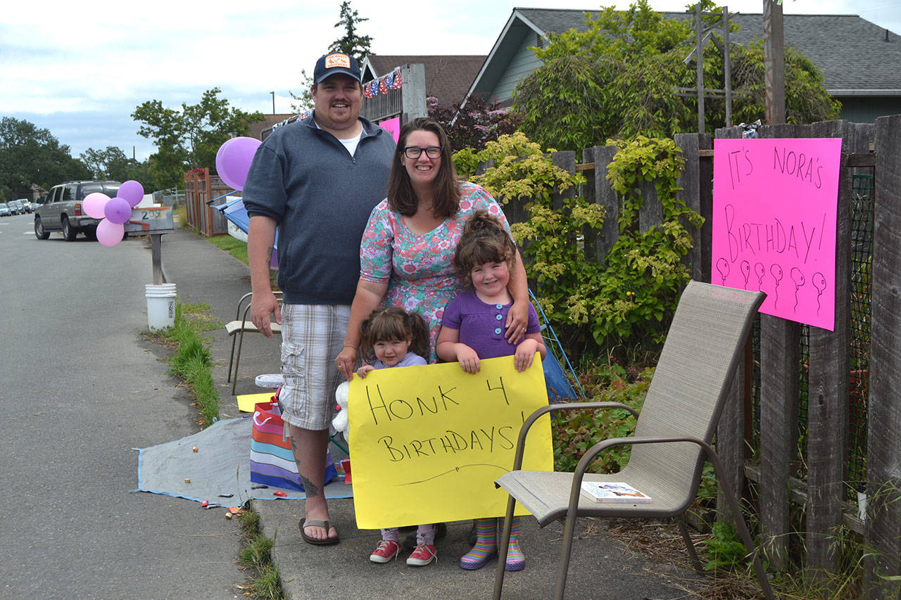 The Hannam family sits outside their downtown Sequim home waving to cars in honor of Nora’s third birthday Saturday, June 20, 2020. (Matthew Nash/Olympic Peninsula News Group)