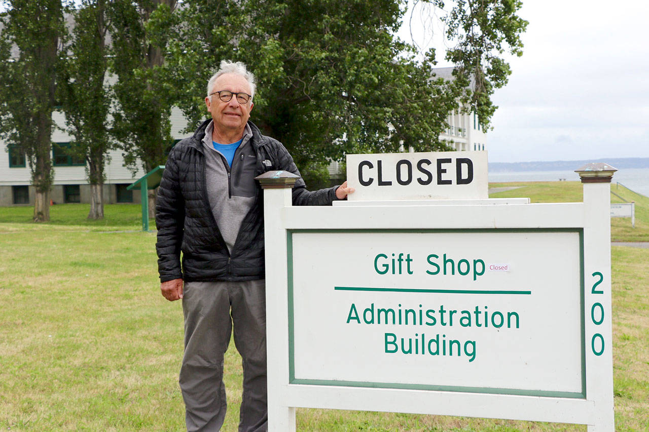 Friends of Fort Worden president Terry LeLievre stands with the sign proclaiming the Fort Worden State Park gift shop closed. The closure has cut into the groups revenues and so it is pursuing other fundraising measures to help it support the park. (Ken Park/Peninsula Daily News)