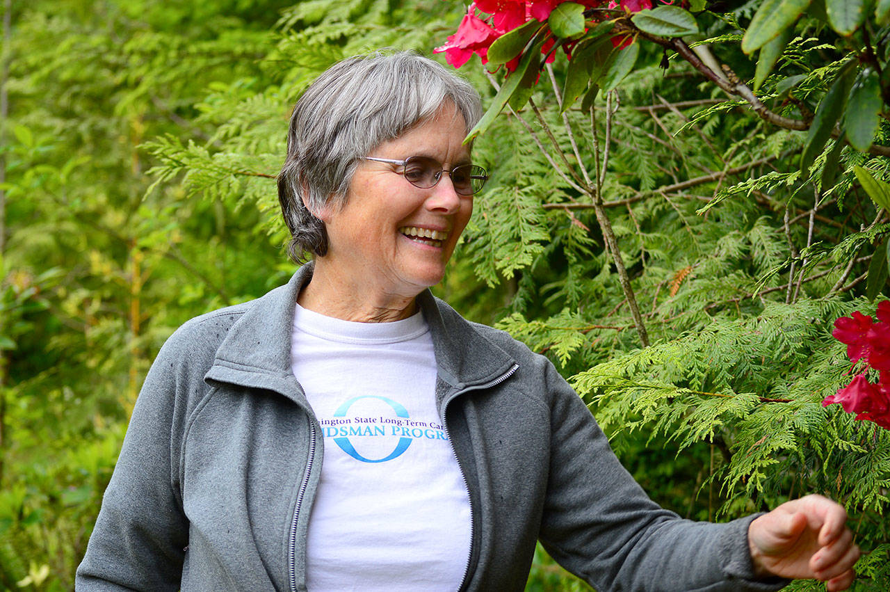 Annie Haggenmiller, wearing her Washington Long-Term Care Ombudsman T-shirt, walks in her Chimacum garden. (Diane Urbani de la Paz/for Peninsula Daily News)