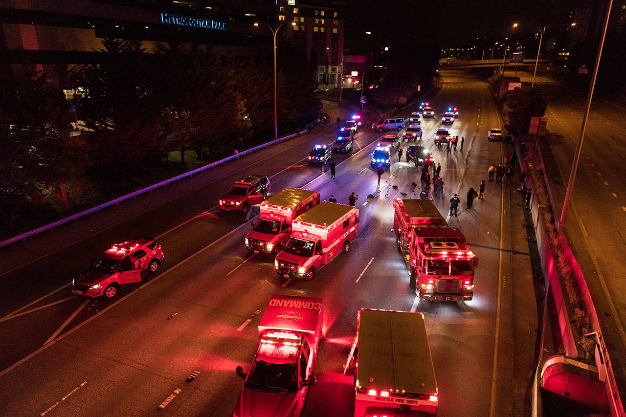 Emergency personnel work at the site where a driver sped through a protest-related closure on the Interstate 5 freeway in Seattle, authorities said early Saturday, July 4, 2020. Dawit Kelete, 27, has been arrested and booked on two counts of vehicular assault. (James Anderson via AP)