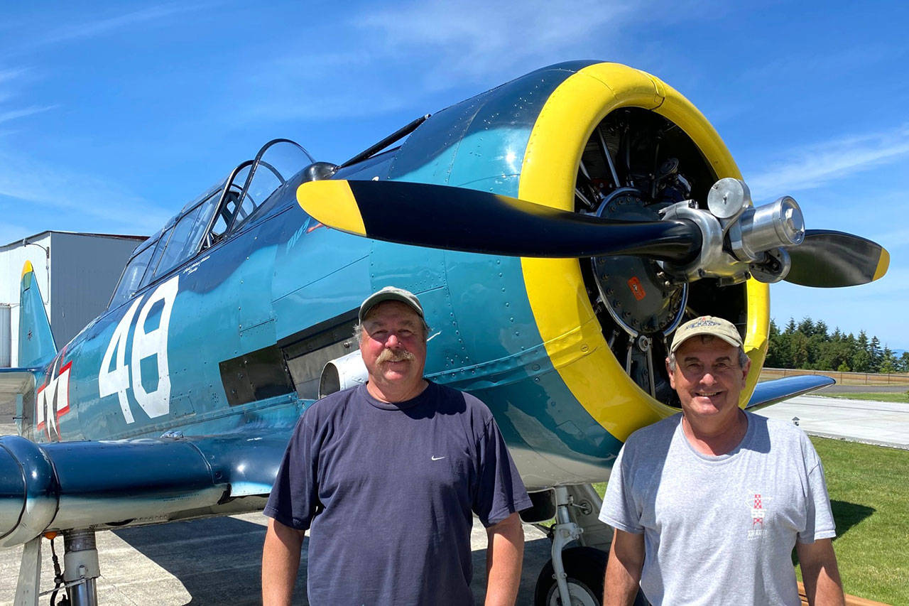 John Johnson, left, and Dave Richardson stand next to Johnson’s T-6 Texan that they will travel with on a Naval aircraft to Hawaii and fly to commemorate the end of World War II 75 years ago. (Photo courtesy of Dave Richardson)