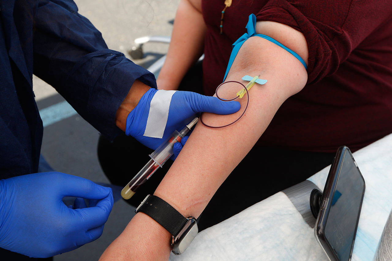 In this Friday, June 12, 2020 file photo, a woman has blood drawn for COVID-19 antibody testing in Dearborn, Mich. Research published on Tuesday, July 21, 2020 suggests that antibodies the immune system makes to fight the new coronavirus may only last a few months in people with mild illness. (AP Photo/Paul Sancya)