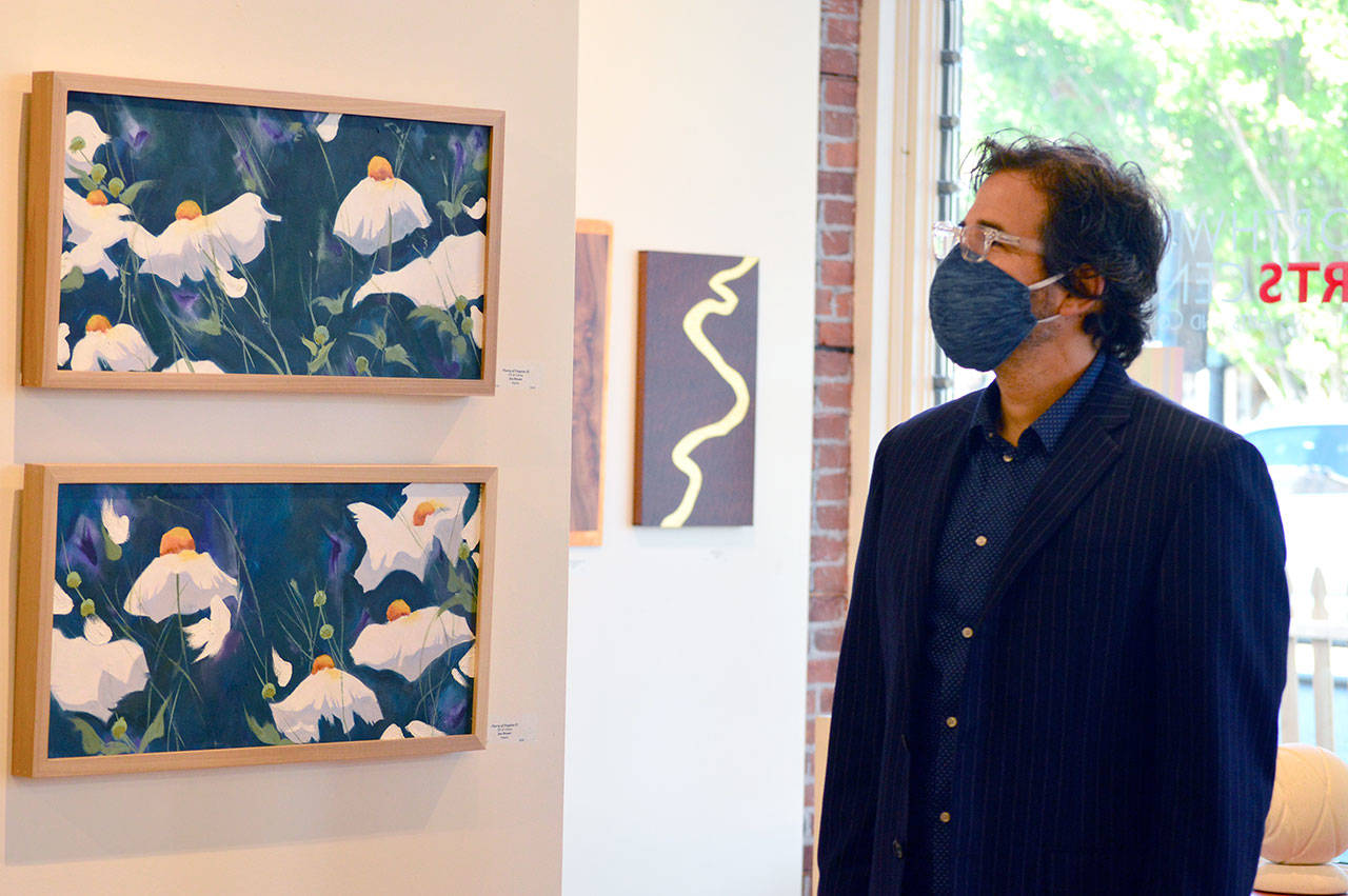 Northwind Arts Center executive director Michael D’Alessandro admires “Flurry of Poppies” by Sequim artist Jinx Bryant. (Diane Urbani de la Paz/for Peninsula Daily News)