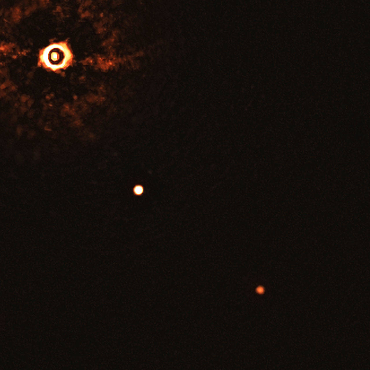 This image made available by the European Southern Observatory in July 2020 shows the star TYC 8998-760-1, upper left, and two giant exoplanets. The image was captured by blocking the light from the young, Sun-like star, allowing for the fainter planets to be detected. The system is about 300 light-years away from Earth. (Bohn et al./ESO via AP)