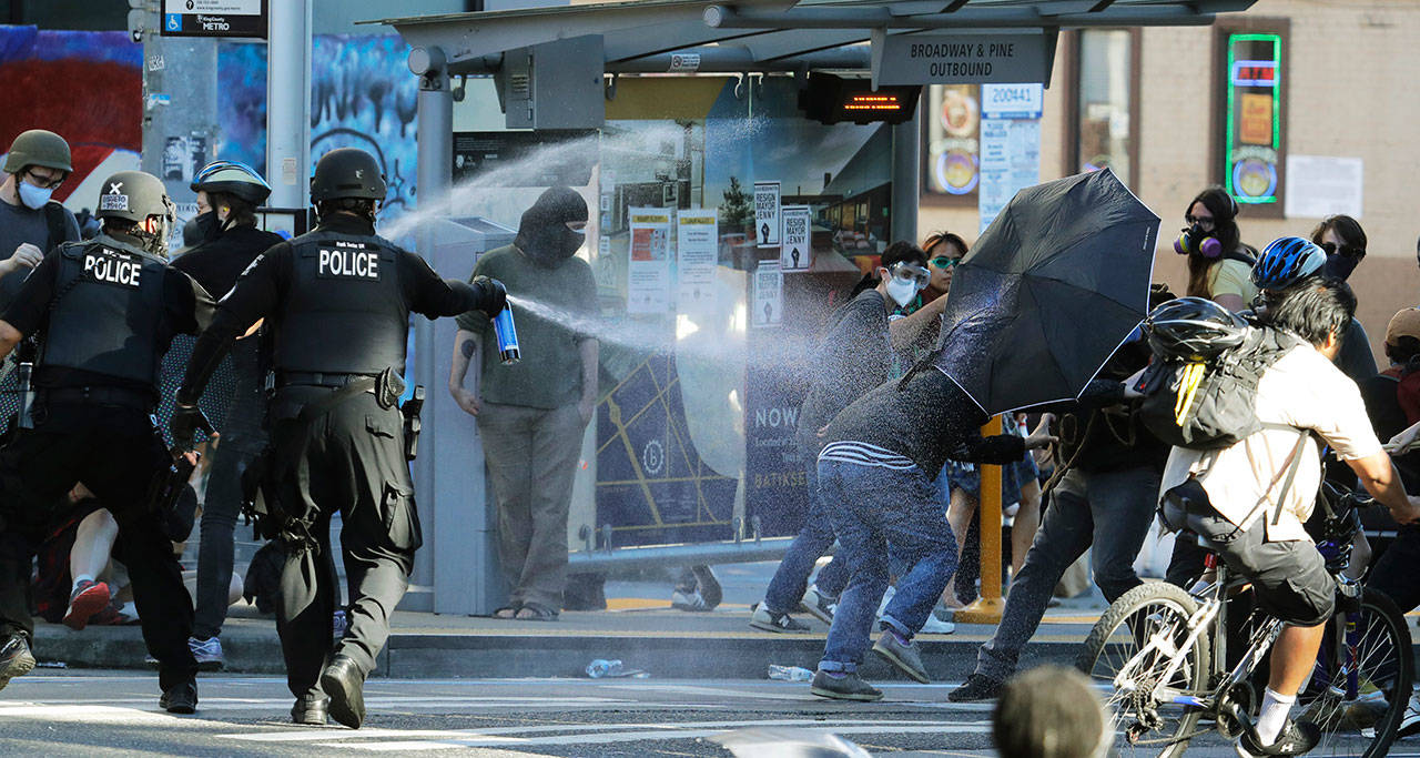 Police pepper spray protesters Saturday, July 25, 2020, near Seattle Central Community College in Seattle. A large group of protesters were marching Saturday in Seattle in support of Black Lives Matter and against police brutality and racial injustice. (Ted S. Warren/Associated Press)