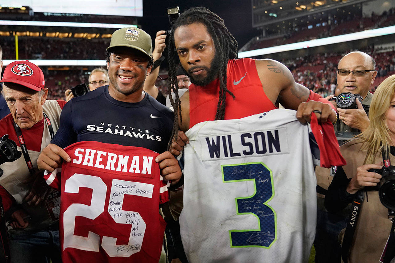 In this Monday, Nov. 11, 2019, photo, Seattle Seahawks quarterback Russell Wilson, left, exchanges jerseys with San Francisco 49ers cornerback Richard Sherman after an NFL football game in Santa Clara, Calif. NFL teams will be prohibited from postgame interactions within 6 feet of each other, so players won’t be allowed to exchange jerseys after games as part of the guidelines to help limit the spread of the coronavirus.The restrictions are outlined in the game-day protocols finalized by the league and NFL Players Association on Wednesday, July 8, 2020. (Tony Avelar/Associated Press file)