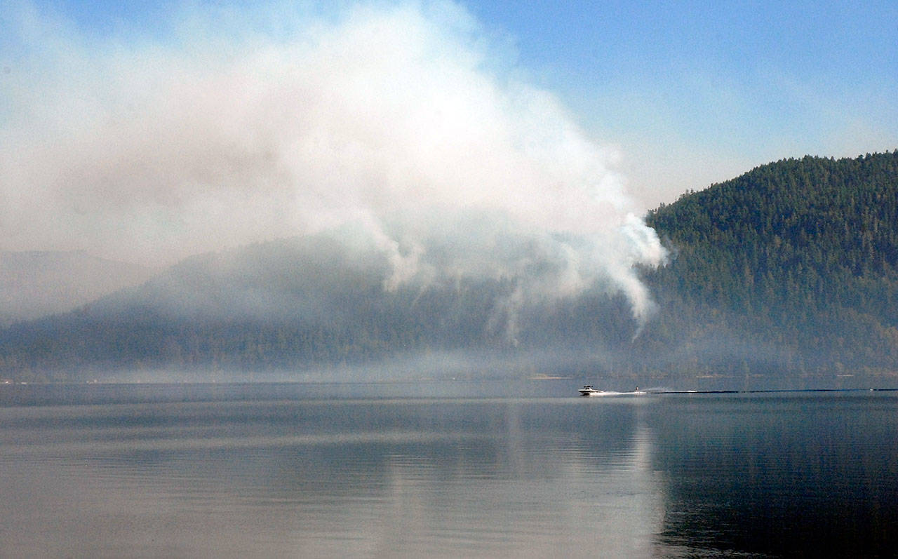 A boat pulling a water skier makes its way past a wildland fire above East Beach Road at Lake Crescent in Olympic National Park on Thursday, July 30, 2020. (Keith Thorpe/Peninsula Daily News)