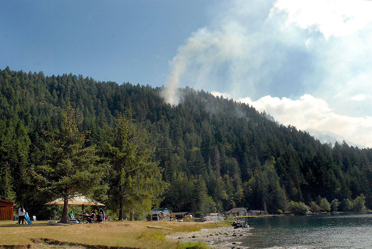 Smoke rises from the East Beach Fire above East Beach Road at Lake Crescent on Saturday as people enjoy the outdoors at Log Cabin Resort in Olympic National Park. The stubborn fire covered 65 acres and was 15 percent contained on Saturday morning. (Keith Thorpe/Peninsula Daily News)