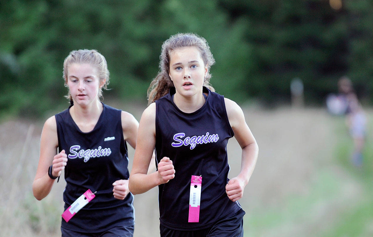 Sequim cross country runners Jessica German, left, and Anastasia Updike run during a fall 2019 meet at Robin Hill County Park. (Michael Dashiell/Olympic Peninsula News Group file)