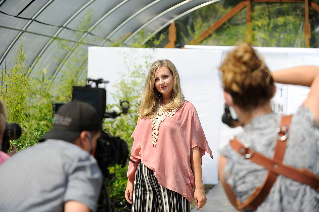 Videographer Silas Crews and photographers Julie Lawrence and Cindy Roth capture Lindsay Sué as she walks the runway for Impact Fashions show in New Dungeness Nursery. (Matthew Nash /Olympic Peninsula News Group)