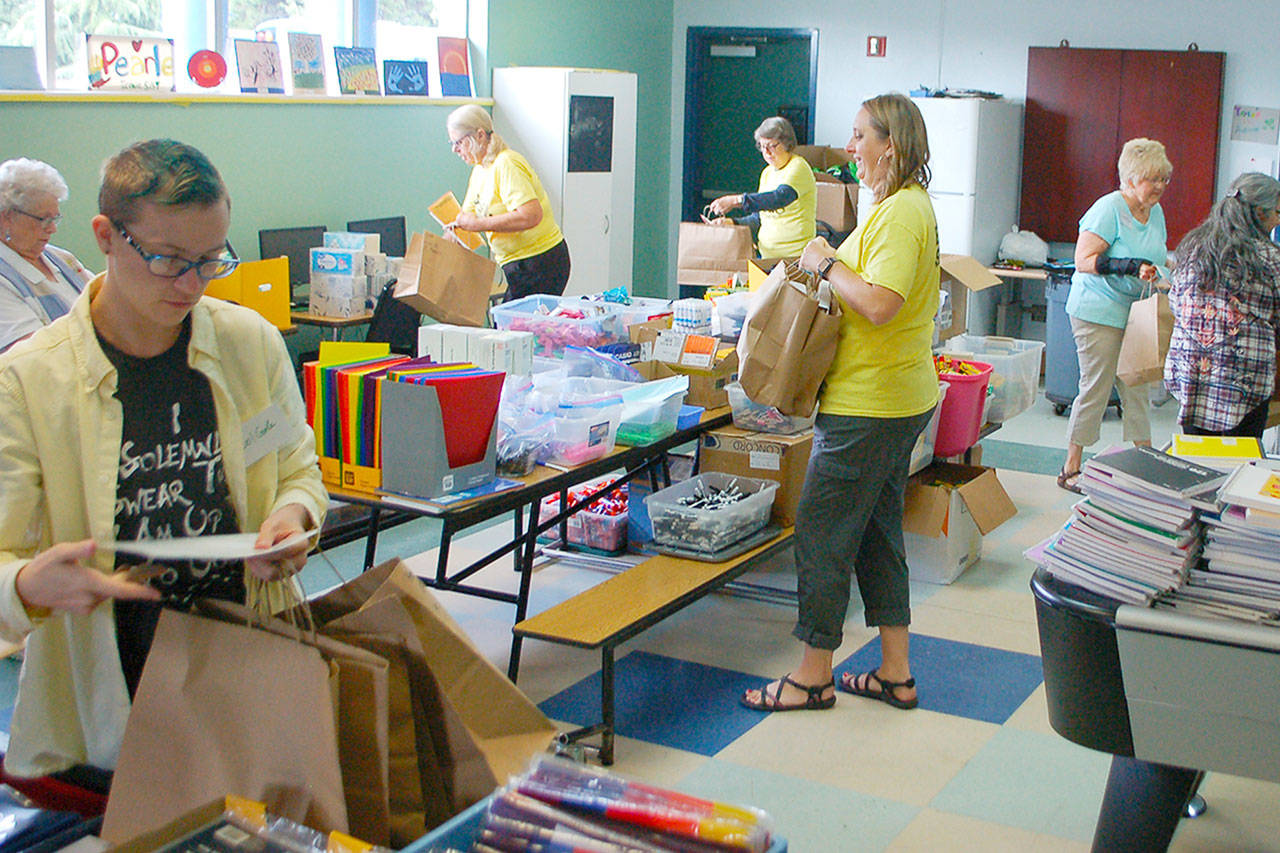 Janet Gray (third from right) and volunteers fill bags with school supplies for students at the 2019 Sequim Back To School Fair. This year’s fair is set for Aug. 29. With a number of health restrictions in place, organizers have changed the event to a “drive through” model. (Conor Dowley/Olympic Peninsula News Group)