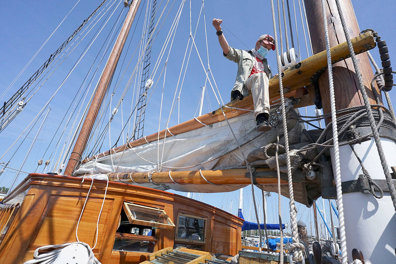 Capt. Nate Seward mouses a shackle Thursday, Aug. 13, 2020, while sitting on a boom of the Schooner Adventuress docked at Port Townsend Boat Haven. (Nicholas Johnson/Peninsula Daily News)