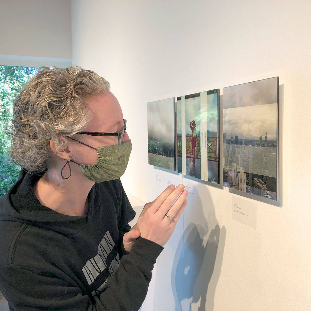 Gallery and Program Director Sarah Jane observes Twyla Sampaco’s acrylic-mounted photograph titled ‘Incoming.’ Three of Sampaco’s works are featured in the Well+Being exhibit. (Photo courtesy of Port Angeles Fine Arts Center)
