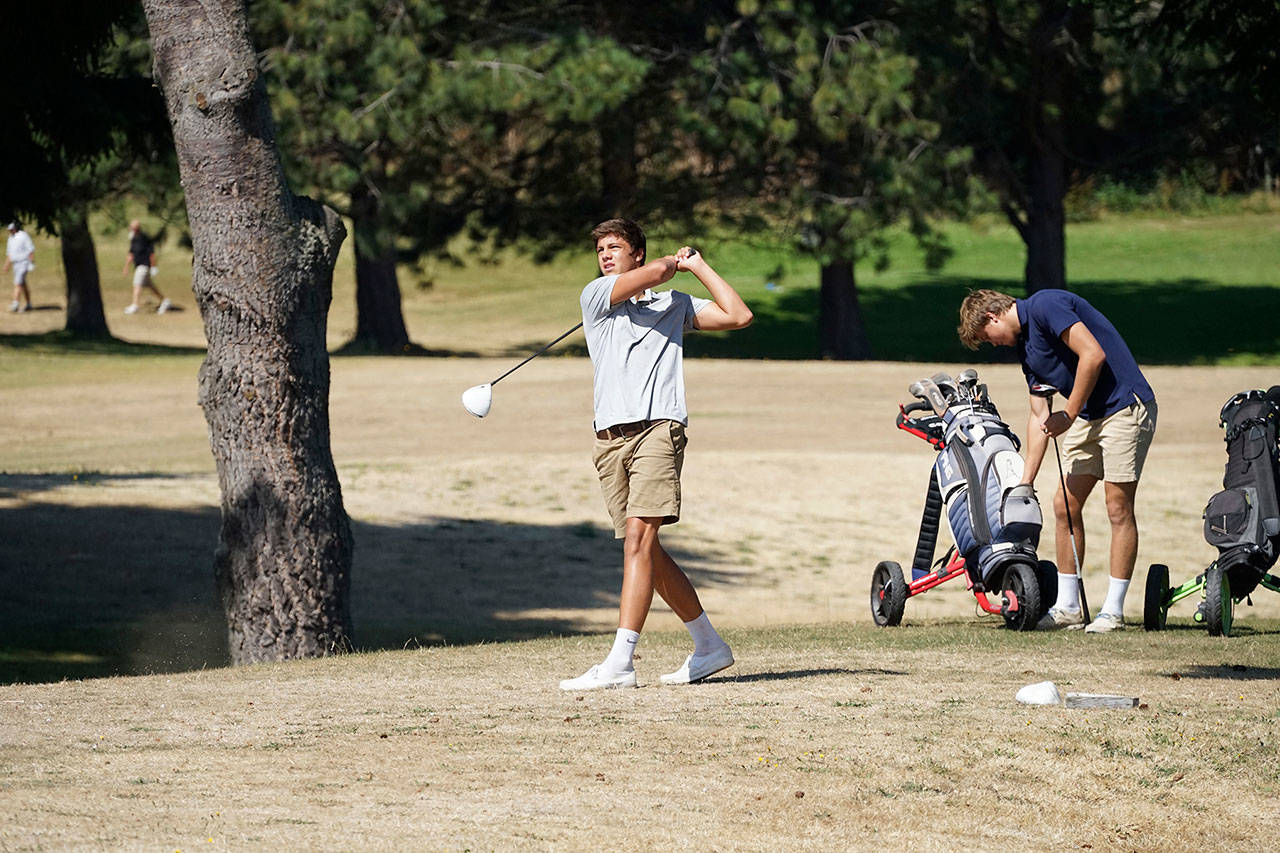 Curtis Johnson, 15, left, tees off while his brother, Conrad Johnson, 17, grabs a ball from his bag Sunday, Aug. 16, 2020, on the third hole at Port Townsend’s municipal golf course. The brothers were in town visiting family. (Nicholas Johnson/Peninsula Daily News)