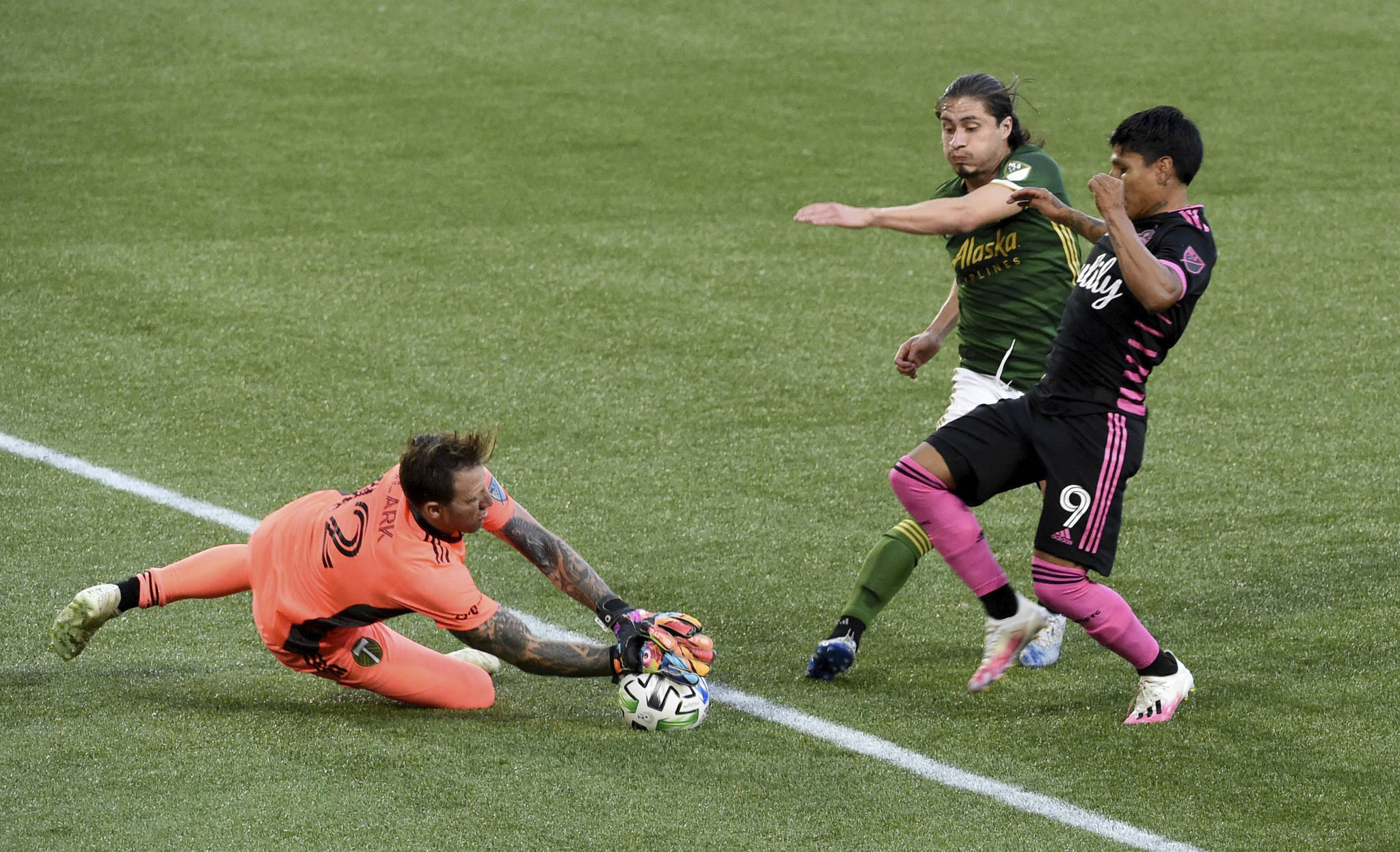 Portland Timbers goalkeeper Steve Clark, left, blocks the shot of Seattle Sounders forward Raul Ruidiaz, right, as Portland Timbers’ Jorge Villafana, center, defends during the first half of an MLS soccer match in Portland, Ore., Sunday, Aug. 23, 2020. (AP Photo/Steve Dykes)
