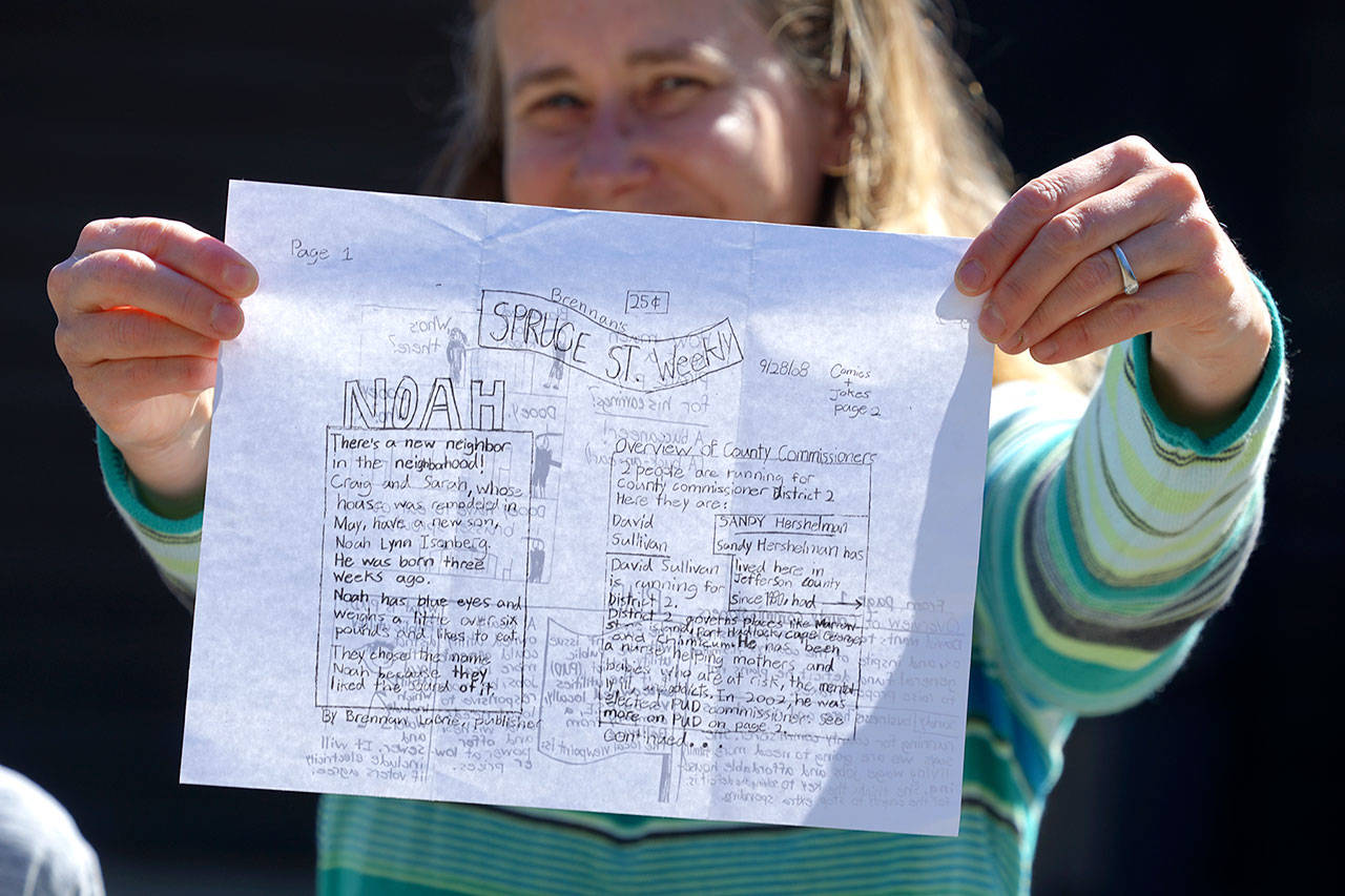 Sarah McNulty, whose two young sons began publishing a homemade newspaper earlier this summer, holds up an old copy of the Spruce St. Weekly, which includes news of the birth of her son Noah. (Nicholas Johnson/Peninsula Daily News)