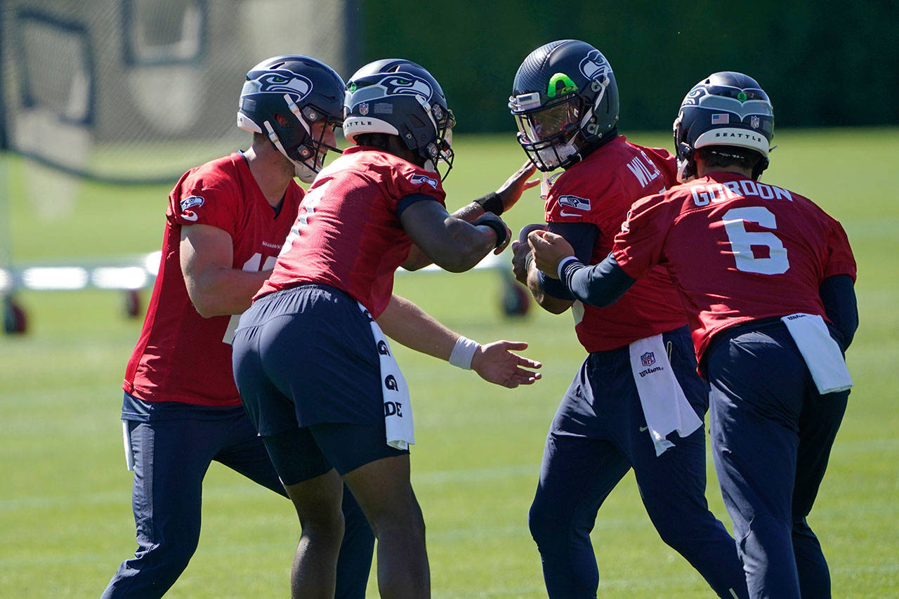 Seattle Seahawks starting quarterback Russell Wilson, second from right, runs a drill where his backup quarterbacks, Danny Etling, left, Geno Smith, second from left, and Anthony Gordon (6) make motions to strip the ball from him during NFL football training camp, Tuesday, Sept. 1, 2020, in Renton, Wash. (Ted S. Warren/Associated Press)