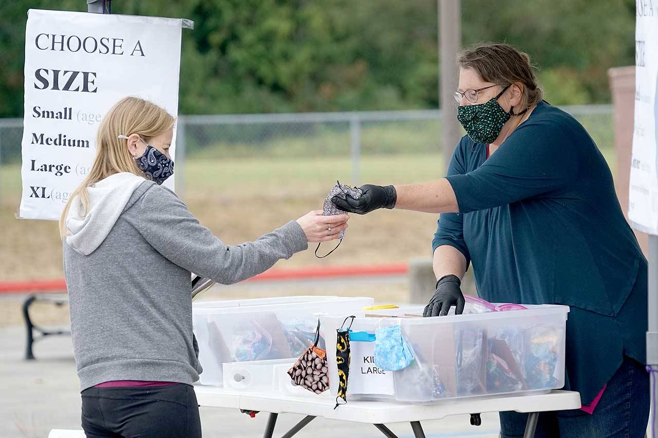 Libby Wennstrom hands a face mask to parent Dawn Cotton on Monday at Blue Heron Middle School in Port Townsend. Cotton was picking up school supplies, as well as masks, for her five children who will be attending Port Townsend schools this year. (Nicholas Johnson/Peninsula Daily News)