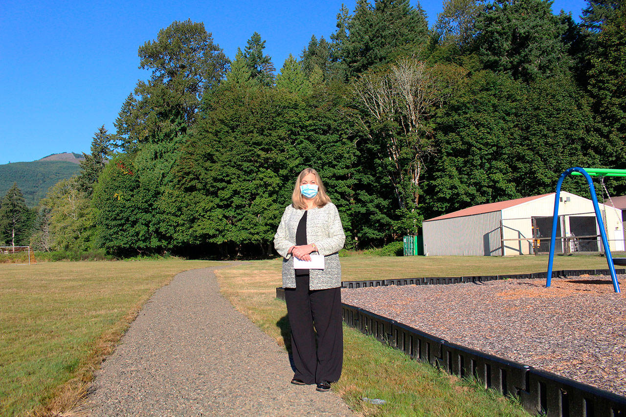 Brinnon School District Superintendent Trish Beathard stands on the districts new walking/running path that was installed over late spring and summer with funding received from a state grant. To her right is the upgraded play area that the district completed last summer with a separate grant award from the same state funding source. (Zach Jablonski/Peninsula Daily News)