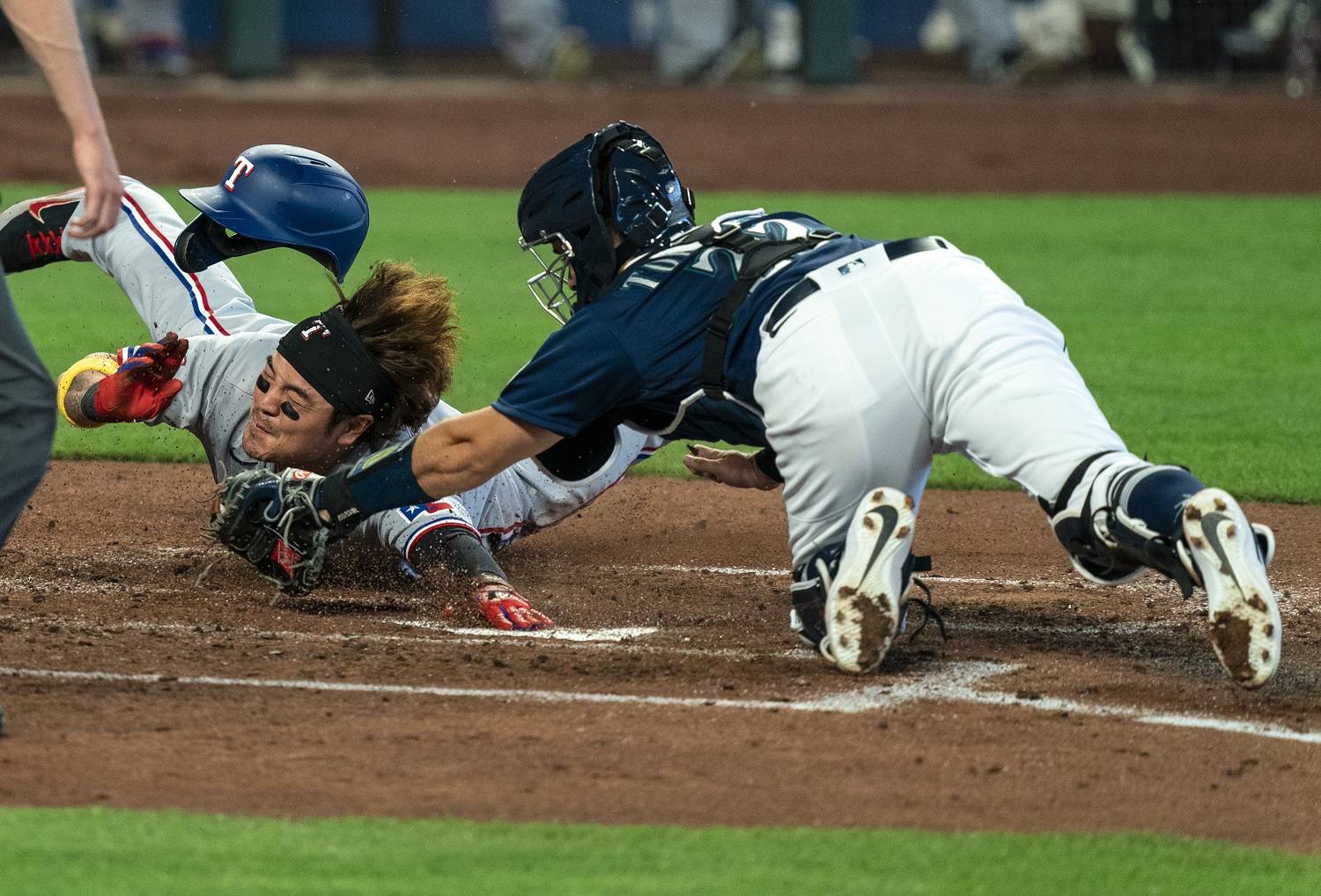 The Texas Rangers’ Shin-Soo Choo, left, touches home plate to score before Seattle Mariners catcher Luis Torrens, right, can make a tag on a two-run double by Rangers’ Joey Gallo off Mariners starting pitcher Marco Gonzales during the fourth inning Monday in Seattle. (Stephen Brashear/Associated Press)