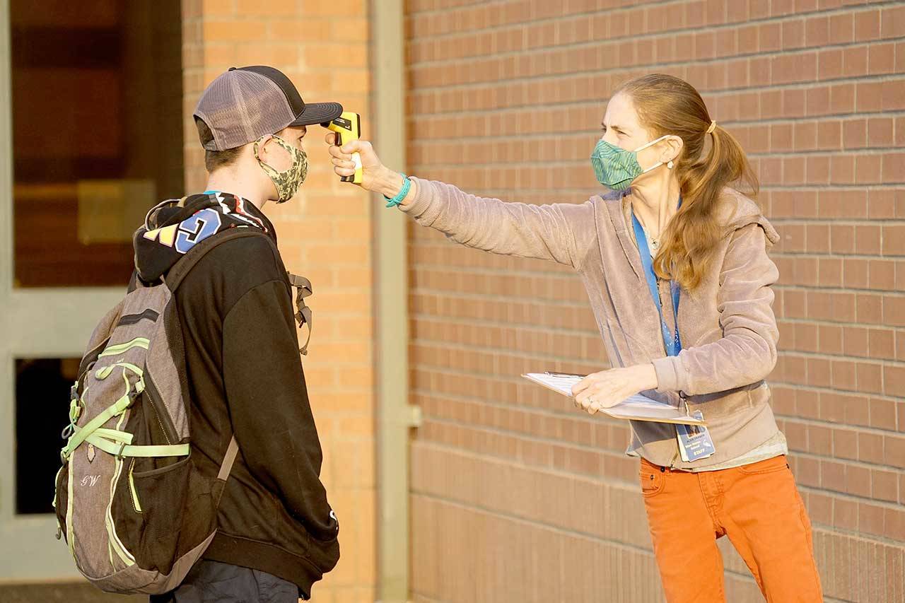 Paraeducator Alice Fraser, right, checks seventh-grader Garret Warrens temperature Tuesday morning outside Blue Heron Middle School in Port Townsend. (Nicholas Johnson/Peninsula Daily News)