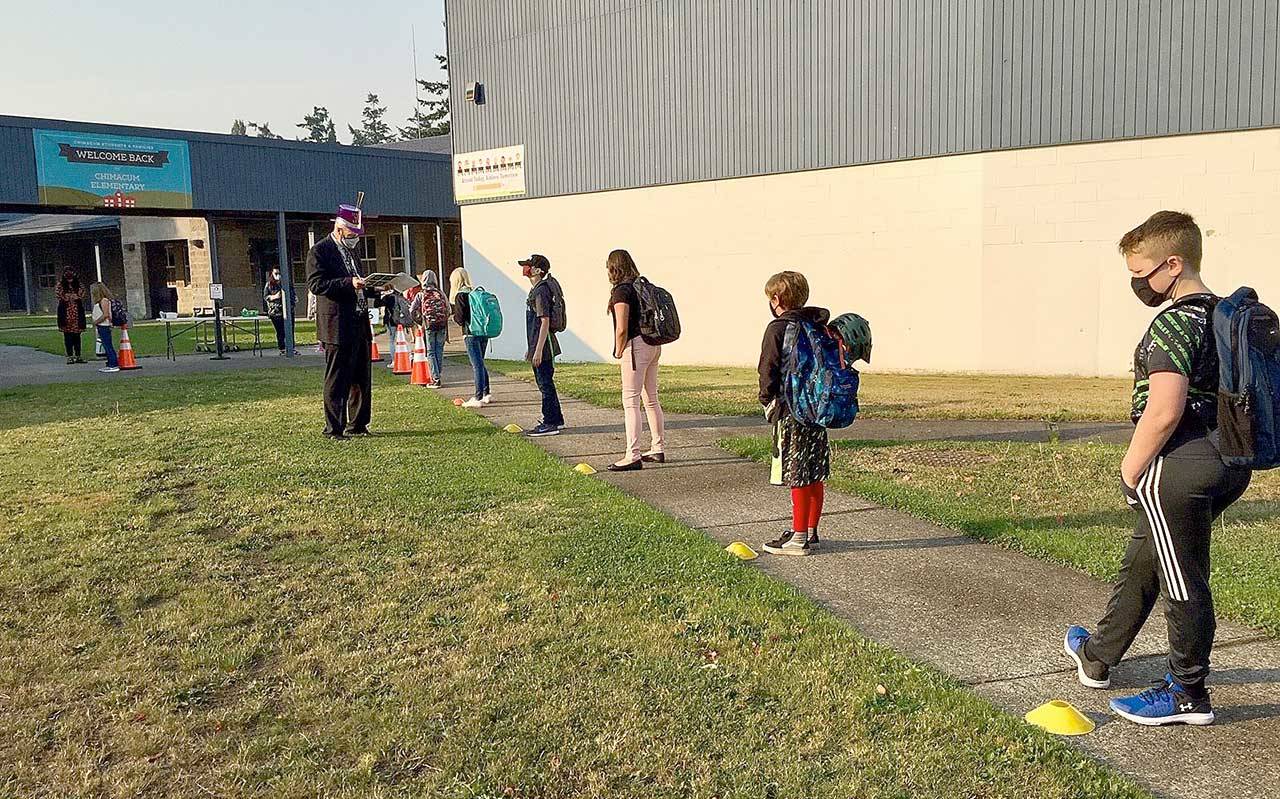 Students stand in a well-spaced line Tuesday morning as they wait to have their temperatures checked on the first day of in-person classes at Chimacum Elementary School in Chimacum. (Jason Lynch)