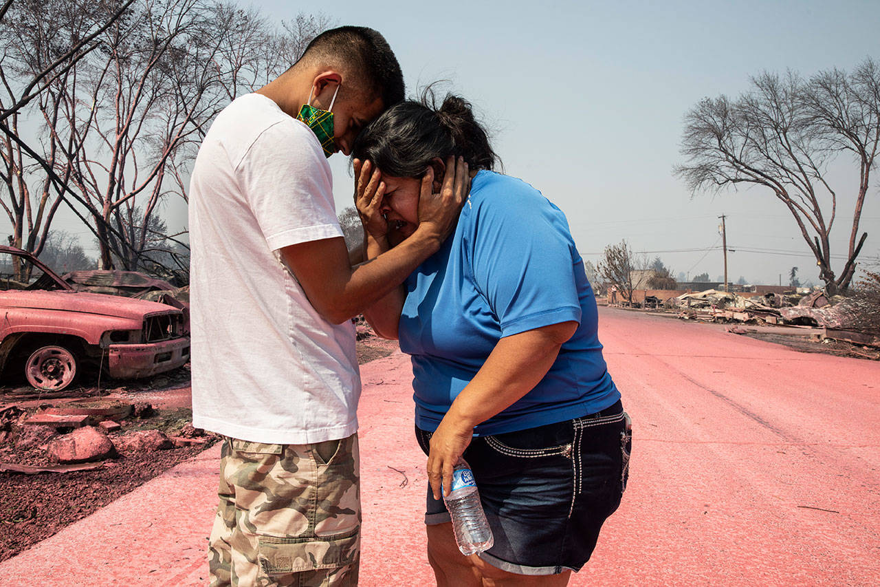 In this Sept. 10, 2020, photo, Dora Negrete is consoled by her son Hector Rocha after seeing their destroyed mobile home at the Talent Mobile Estates in Talent, Ore., after wildfires devastated the region. Two unusual weather phenomena combined to create some of the most destructive wildfires the West Coast states have seen in modern times. (Paula Bronstein/Associated Press)