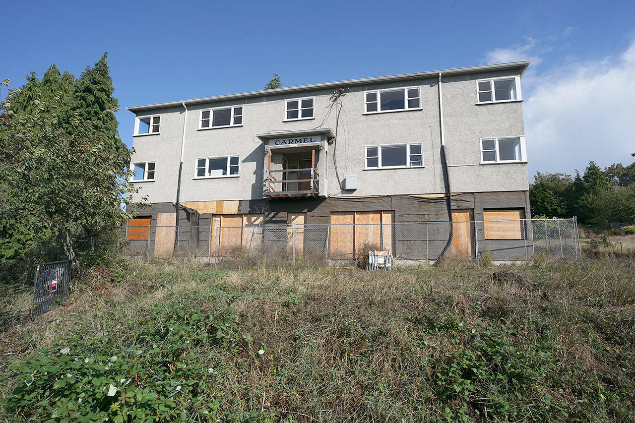Fencing and overgrown grass surround the unfinished affordable housing apartment building at the corner of Cherry and Van Ness streets in Port Townsend. (Nicholas Johnson/Peninsula Daily News)