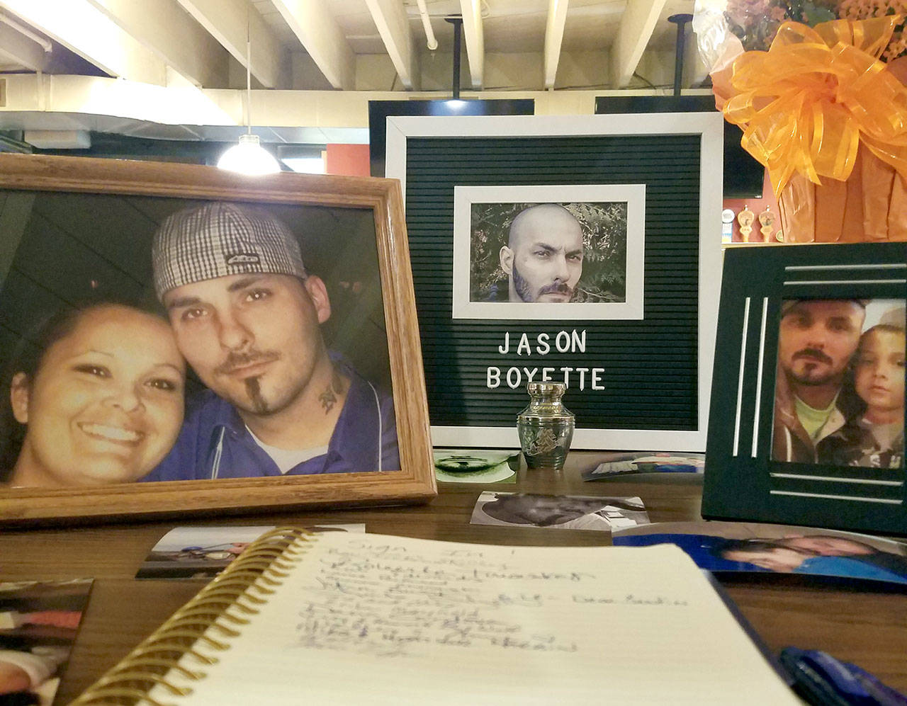 Framed photos and an urn filled with ashes are displayed inside The Tin Brick during a wake for chef Jason Boyette on Sept. 21 in downtown Port Townsend. At left is Boyette with his partner of 16 years, Amanda Timentwa, and at right is Boyette with his son Elias, 5. (Nicholas Johnson/Peninsula Daily News)