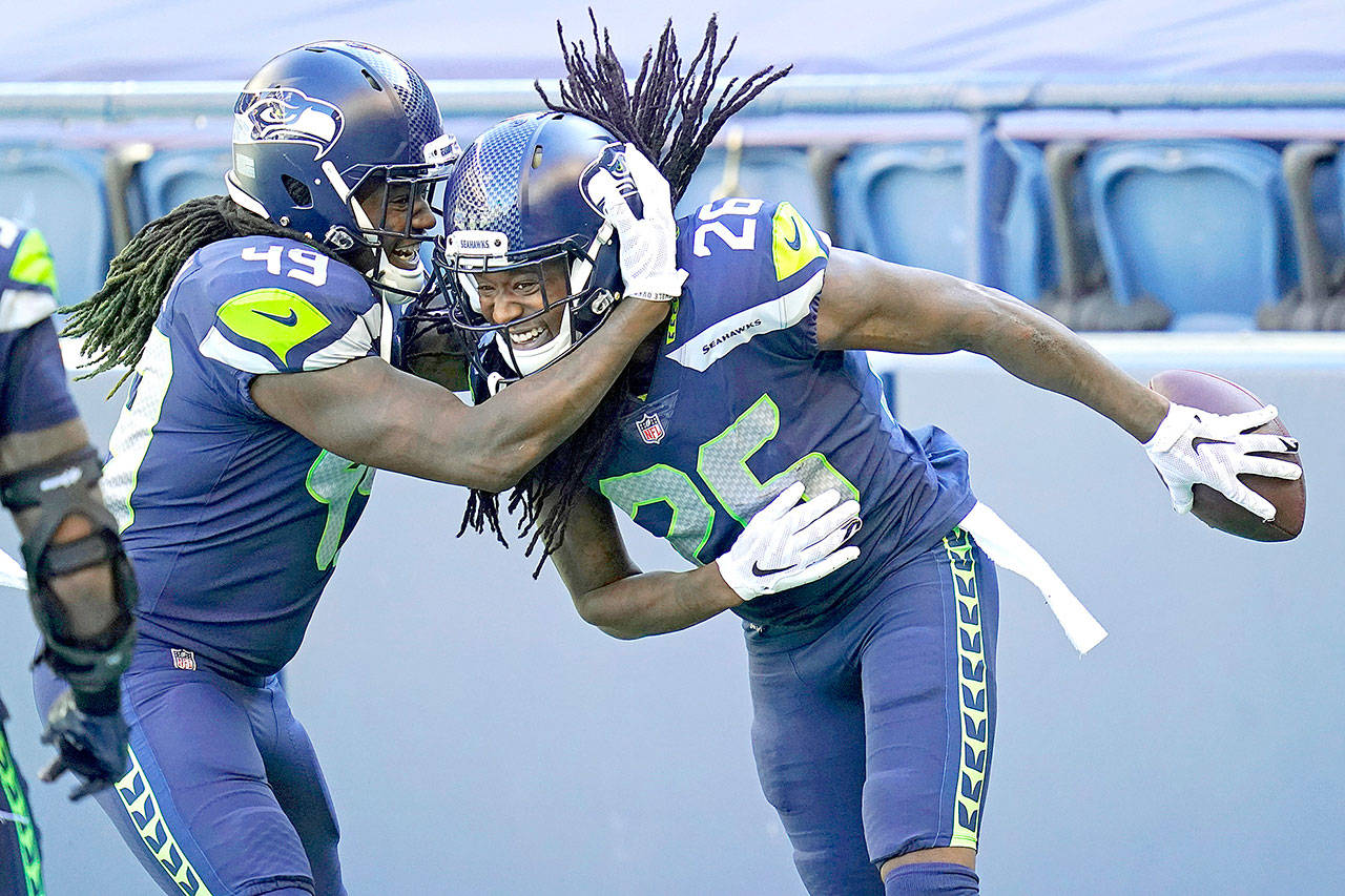 Seattle Seahawks cornerback Shaquill Griffin (26) is greeted by his twin brother, outside linebacker Shaquem Griffin (49), after Shaquill Griffin intercepted a pass against the Dallas Cowboys during the first half Sunday in Seattle. (Elaine Thompson/The Associated Press)