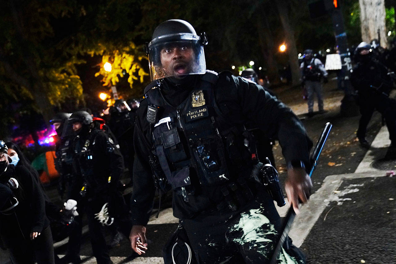 A Portland police officer pushes back protesters Saturday, Sept. 26, 2020, in Portland. The protests, which began over the killing of George Floyd, often result frequent clashes between protesters and law enforcement. (John Locher/Associated Press)
