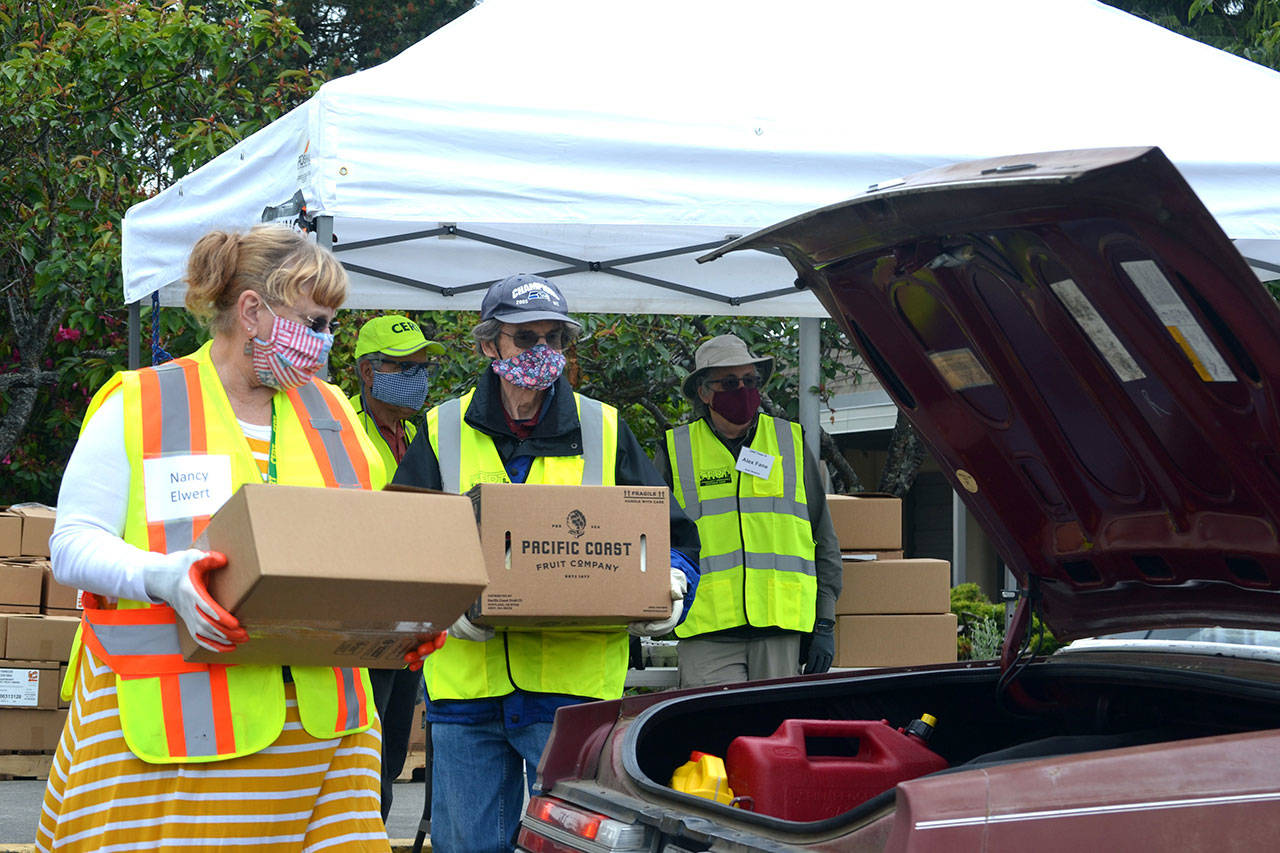 Volunteers Nancy Elwert and Bruce Leigh with Community Emergency Response Teams (CERT) get ready to place food boxes in a trunk at Sequim High School on June 10, 2020. The program, now held at Trinity United Methodist Church, continues twice monthly through December. (Matthew Nash/Olympic Peninsula News Group file)