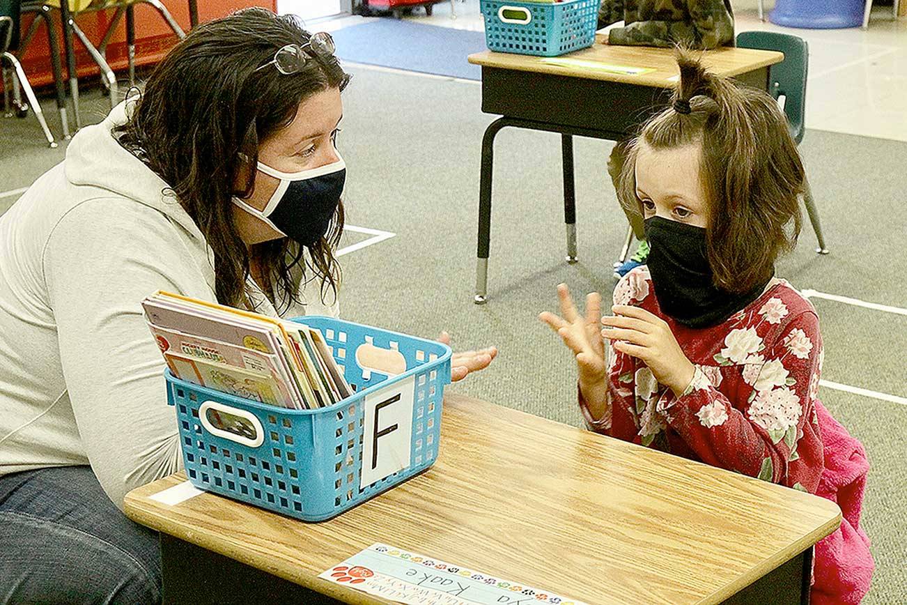 Alicia Kaake, left, talks to her daughter Freya Kaake as she sits in her seat for the first time in Mrs. Teague-Schmeltz’s classroom at Hamilton Elementary School in Port Angeles. Monday was the first day of school for kindergartners and first-graders in the Port Angeles School District. Desks are at least 6 feet apart and all students and teachers are wearing face masks. (Dave Logan/for Peninsula Daily News)