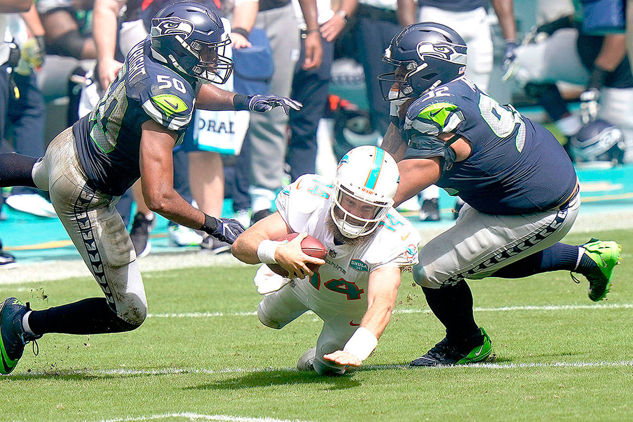 Miami Dolphins quarterback Ryan Fitzpatrick (14) falls as Seattle Seahawks outside linebacker K.J. Wright (50) and defensive tackle Bryan Mone (92) attempt to tackle, during the second half of an NFL football game, Sunday, Oct. 4, 2020, in Miami Gardens, Fla. (AP Photo/Lynne Sladky)