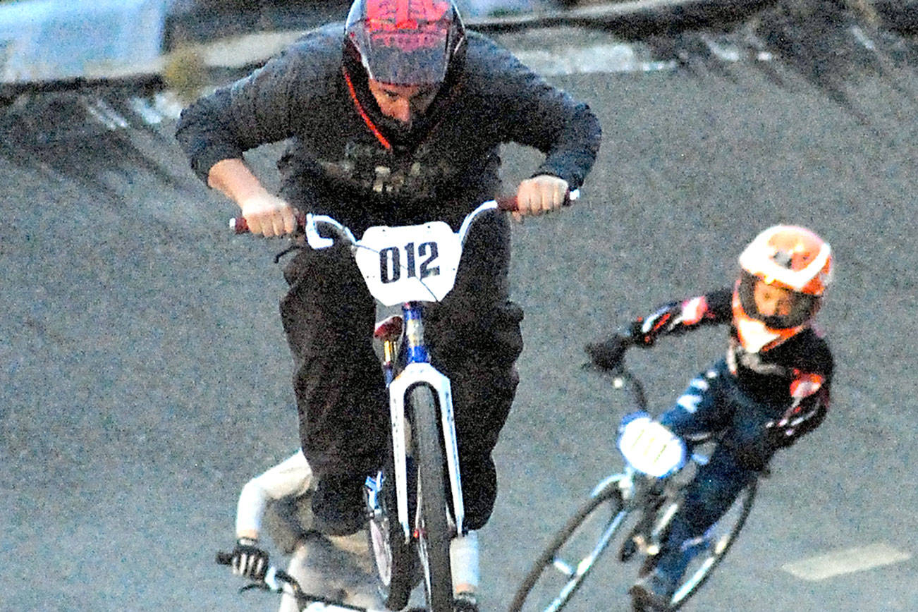 Keith Thorpe/Peninsula Daily NewsAaron Petersen (012) of Port Angeles leads Sam Brown (078) of Port Angeles in the novice category at the Lincoln Park BMX Track on Thursday night under the track's new lights. The track is back open for competition.