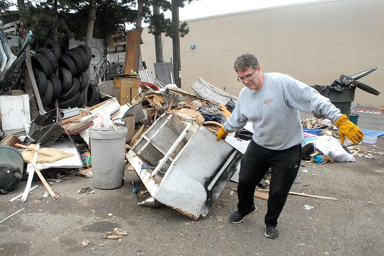 Keith Thorpe/Peninsula Daily NewsMichael LaGrange, store manager of the Lincoln Street Safeway in Port Angeles, pull debris from trash pile for disposal last week from a company-leased parking lot behind the grocery.