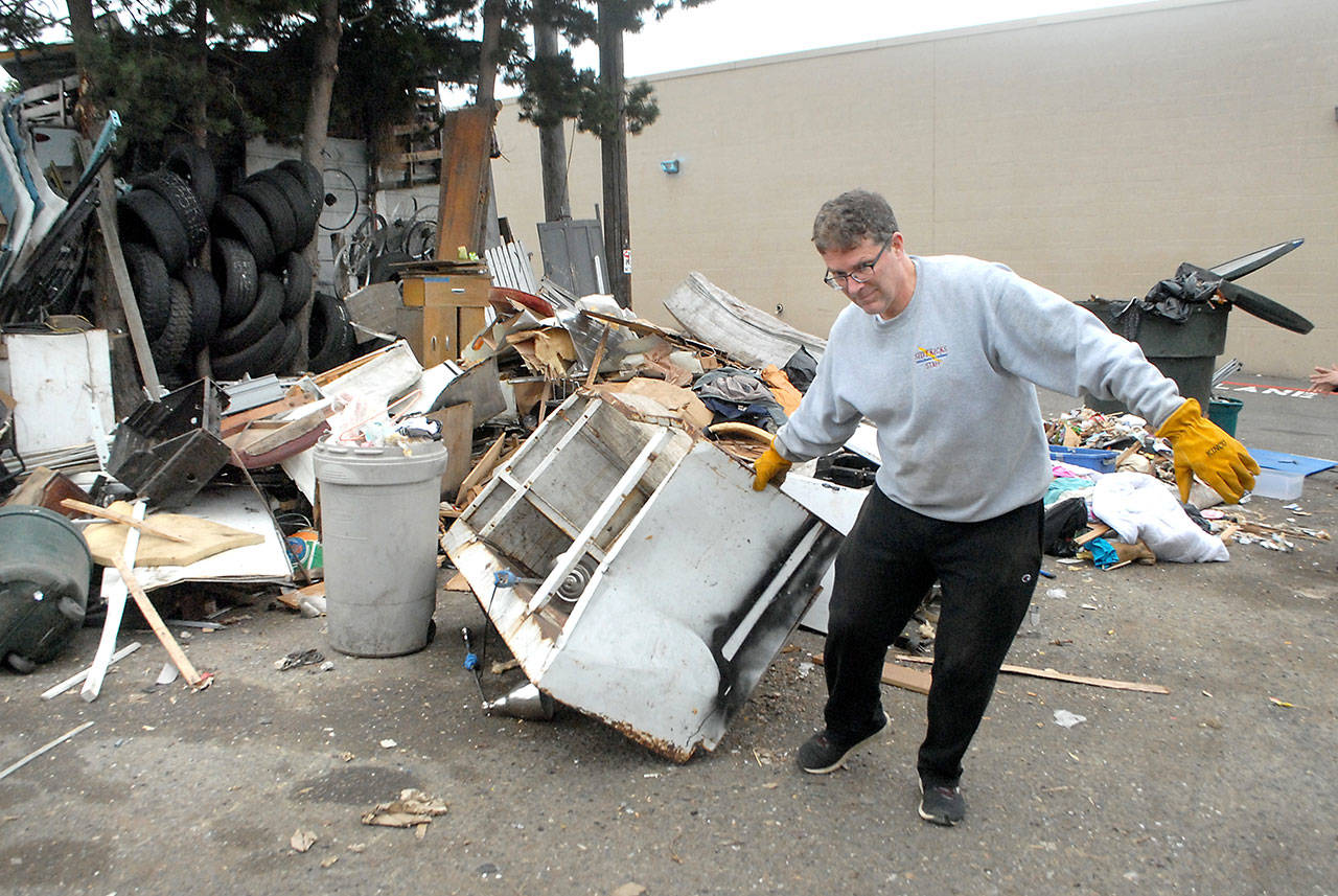 Michael LaGrange, store director of the Lincoln Street Safeway in Port Angeles, pull debris from trash pile for disposal last week from a company-leased parking lot behind the grocery. (Keith Thorpe/Peninsula Daily News)