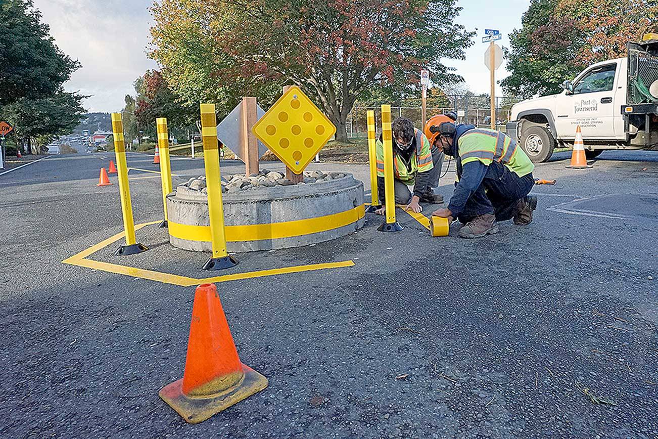 Kurt Hardesty, left, and Chris MacDonald of the city of Port Townsend's transportation crew apply yellow tape to the roadway around a mini traffic circle Monday morning in the center of Washington Street at Cass Street next to County Courthouse Park in Port Townsend. (Nicholas Johnson/Peninsula Daily News)