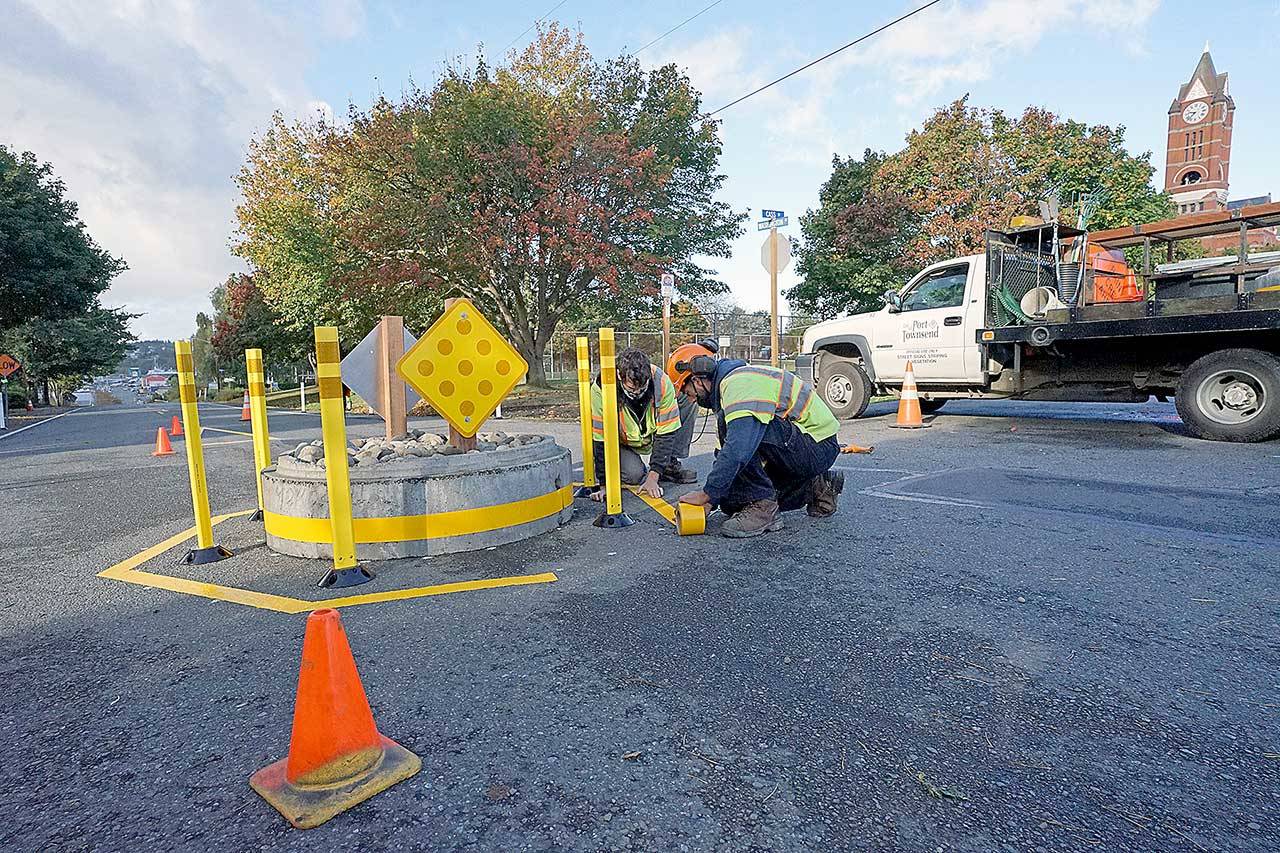 Kurt Hardesty, left, and Chris MacDonald of the city of Port Townsend’s transportation crew apply yellow tape to the roadway around a mini traffic circle Monday morning in the center of Washington Street at Cass Street next to County Courthouse Park in Port Townsend. (Nicholas Johnson/Peninsula Daily News)