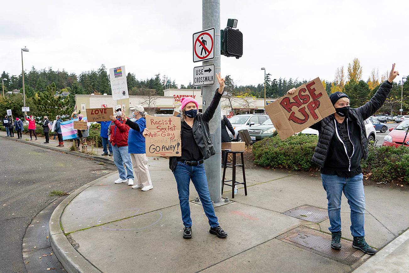 Cara Griswold, center, and Susan Larson lead a rally to honor the life and legacy of former Supreme Court justice Ruth Bader Ginsburg during a Women's March in Port Townsend on Saturday. About 60 or more showed up on all four corners of Sims Way and Haines Place to hold up signs and wave to passing automobiles. (Steve Mullensky/for Peninsula Daily News)