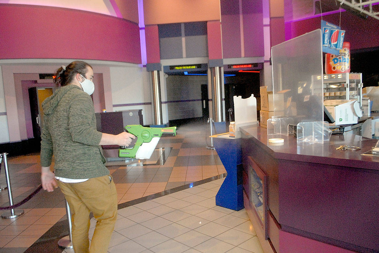 Deer Park Cinema manager Casey Chapman sprays disinfectant mist around the concession stand of the Port Angeles theater complex lobby Thursday, Oct. 22, 2020, in preparation for reopening Oct. 30. (Keith Thorpe/Peninsula Daily News)