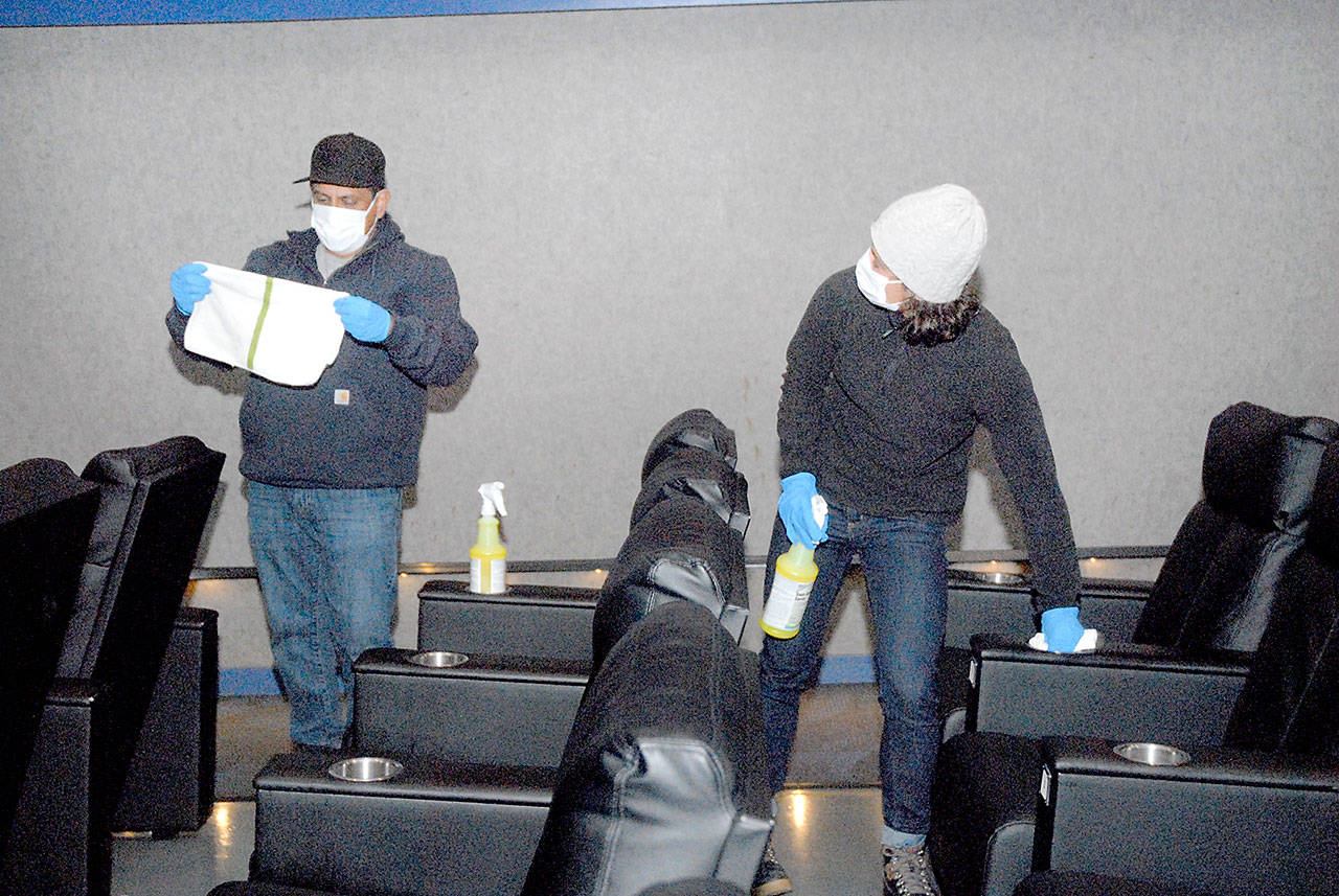 José Martinez, general manager of Deer Park Cinema, left, and maintenance worker Megan Cook wipe down seats in the Port Angeles theater complex Thursday, Oct. 22, 2020. (Keith Thorpe/Peninsula Daily News)