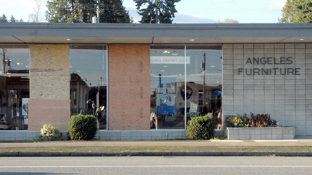 Plywood panels cover a pair of windows at Angeles Furniture and Mattress Co., 1114 E. First St., on Saturday in Port Angeles. (Keith Thorpe/Peninsula Daily News)