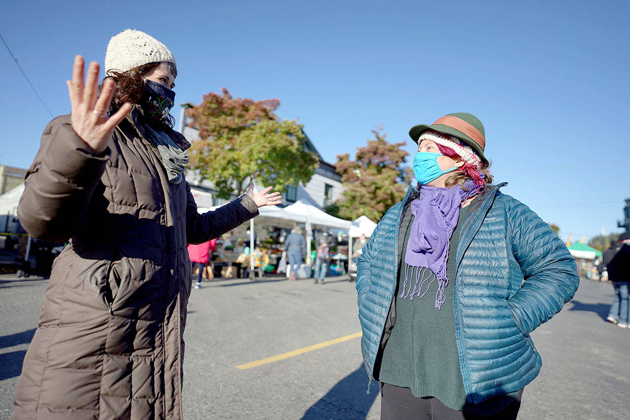 Amanda Milholland, left, and Deirdre Morrison talk while strolling through the Port Townsend Farmers Market on Saturday in uptown Port Townsend. Morrison is taking over for Milholland as market manager for the Jefferson County Farmers Markets. While Milholland has started her new role as produce manager at the Port Townsend Food Co-op, she plans to train her successor through the end of the market season in December. (Nicholas Johnson/Peninsula Daily News)