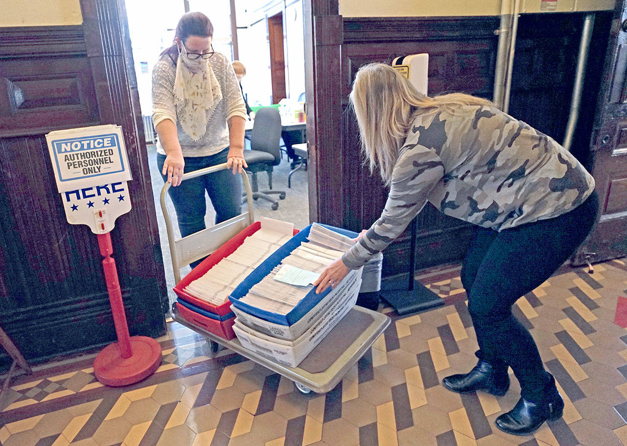 Barb Ferguson, left, and Brenda Huntingford, both employees with the Jefferson County Auditor’s Office, transfer trays of ballots to a room for opening and hands-on review after their signatures were checked against a state database Tuesday, Oct. 27, 2020, at the Jefferson County Courthouse in Port Townsend. (Nicholas Johnson/Peninsula Daily News)