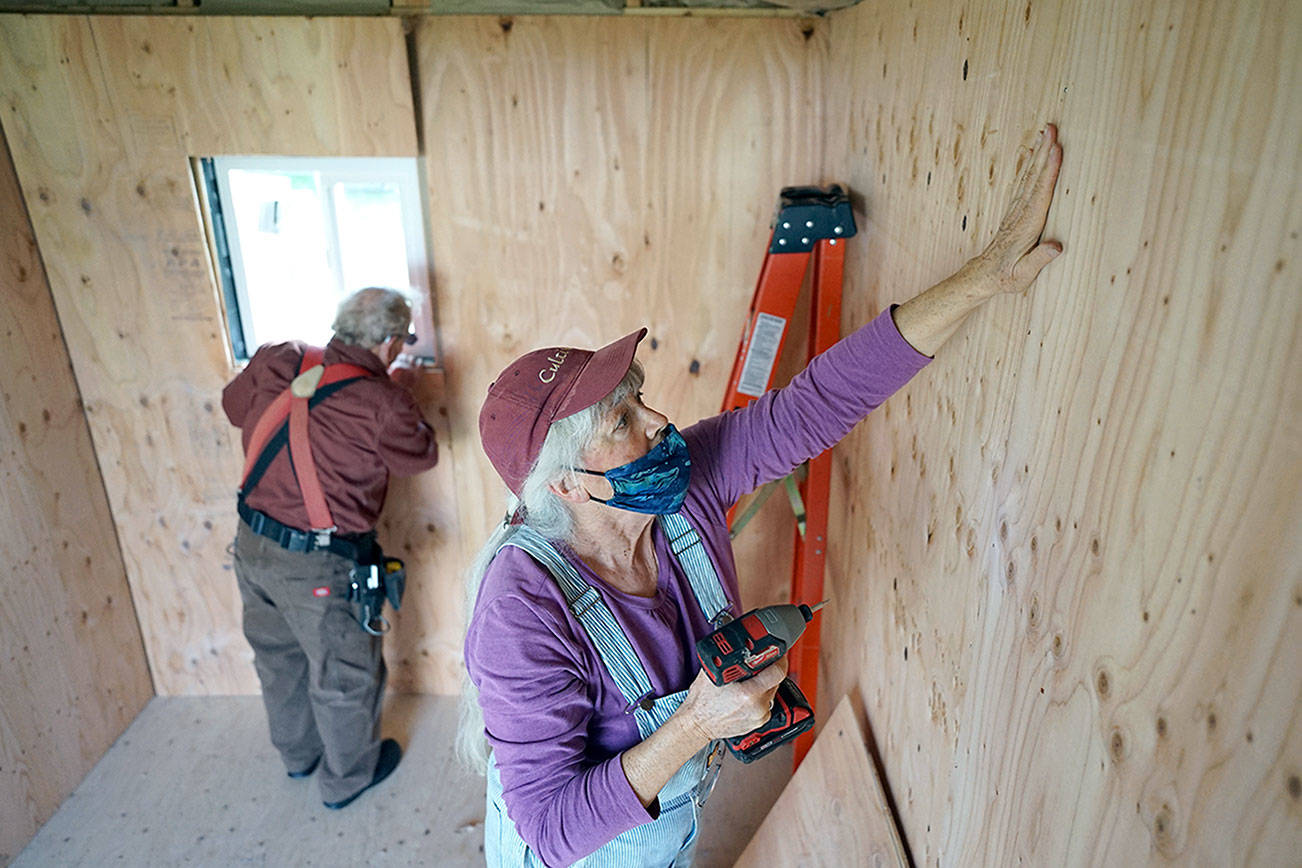 Judy Alexander of Port Townsend installs interior siding with Peter Bonyun while working on an emergency shelter. Alexander and Bonyun are two of the three
people who started the Community Build Project, which aims to provide temporary-use shelters for the homeless during the coming winter months. (Nicholas Johnson/Peninsula Daily News)