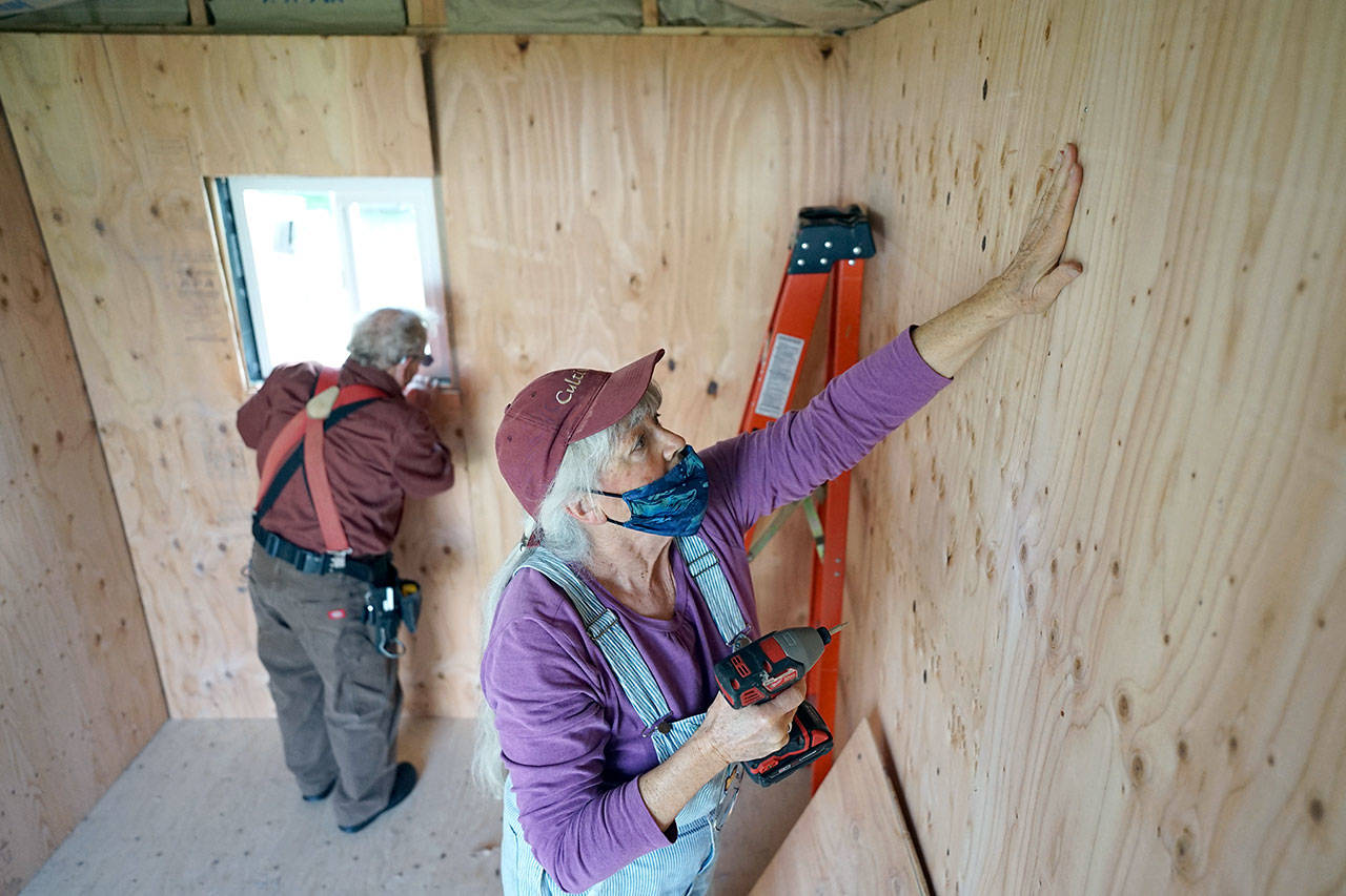 Judy Alexander of Port Townsend installs interior siding with Peter Bonyun while working on an emergency shelter. Alexander and Bonyun are two of the three people who started the Community Build Project, which aims to provide temporary-use shelters for the homeless during the coming winter months. (Nicholas Johnson/Peninsula Daily News)