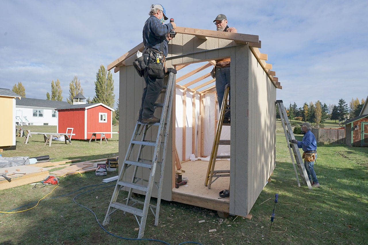Blue Heron Construction co-owner Randy Welle, from left, Greg Kossow and Larry Morrell work to construct an emergency shelter Thursday afternoon in Port Townsend. The neighbors formed a volunteer group to build one shelter over several days as part of the Community Build Project, which aims to provide temporary-use shelters for the homeless during the coming winter months. (Nicholas Johnson/Peninsula Daily News)